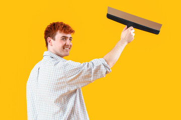 Young man with putty knife on yellow background