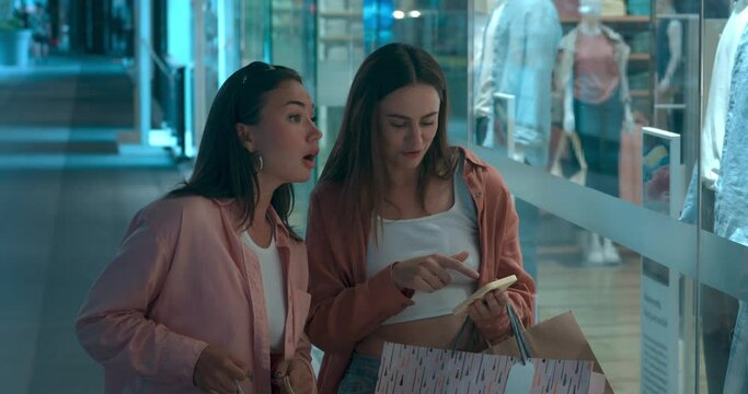 Women at mall looking showcases lively talk about shopping Showcases display trends sparking happiness. Showcases symbol of shopping bliss on new clothes Embracing excitement of shopping.