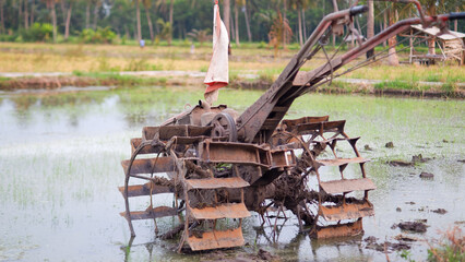 Rice field tractor machine on watery agricultural land in the countryside in Indonesia.