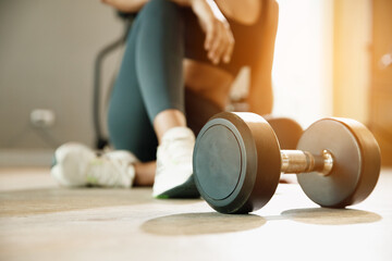 Close up Dumbbell on floor in gym with woman background. Object goal weightlifting bodybuilding.