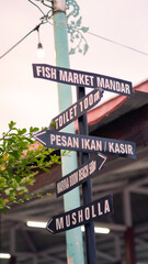 Fototapeta premium Sign with Arrows indicating directions to different places in the traditional fish market at Banyuwangi.