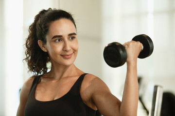 Fototapeta na wymiar Healthy strong latina female holding dumbbells lifts weights exercise in gym. sport training weights fitness, Exercise to lose weight, take care of health.