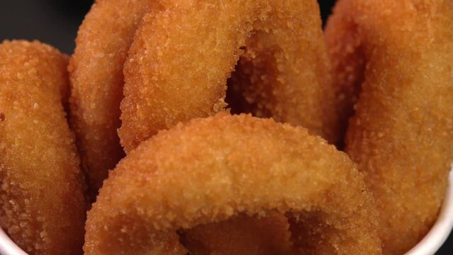 Crisp french-fried onion rings starter dipped in batter or bread crumbs close up. Perfect for promoting fast food, supermarket exhibit, food truck, grab-and-go treats, roadside eatery
