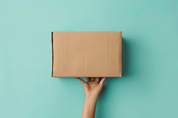 female hand holding brown cardboard box on light blue background delivery mockup