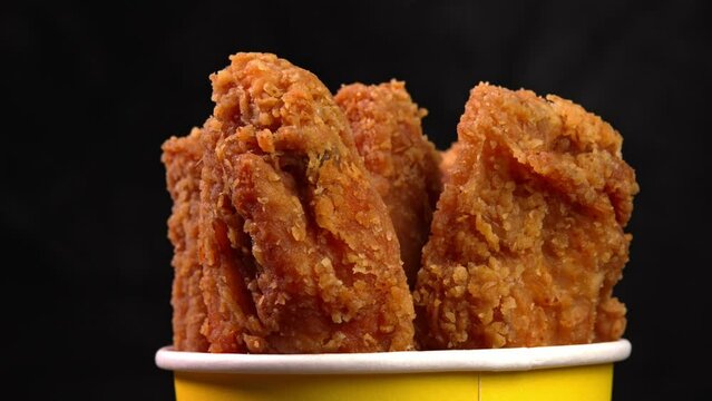 Hot deep-fried chicken wings appetizers coated in bread crumbs on dark background. Footage suitable for promoting fast food, takeaway snacks, roadside eatery, retail exhibit, mobile food service