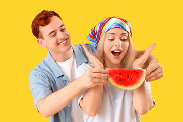 Young beautiful man and woman with slice of fresh watermelon on yellow background