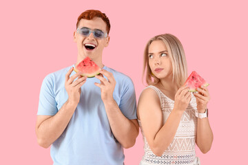 Young beautiful man and woman with slices of fresh watermelon on pink background