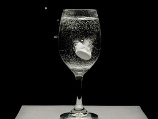 Alka seltzer dropped in a wine glass filled with water.
