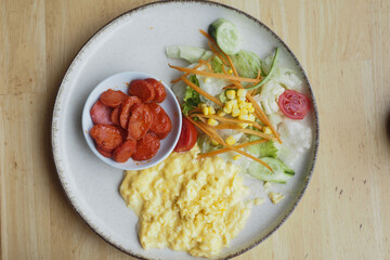 morning breakfast with Scrambled eggs and sausage on a white plate 