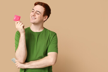 Young man with condom on beige background. Safe sex concept