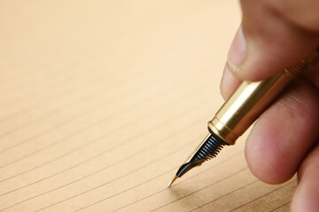 man's hand writing with a fountain pen on paper 