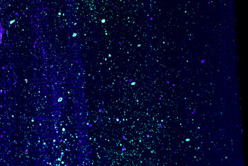 flecks of fluorescent paint on canvas lit by blacklight