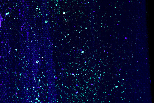 flecks of fluorescent paint on canvas lit by blacklight