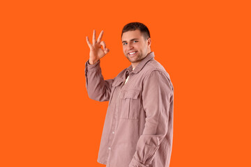 Handsome man showing OK on orange background