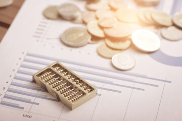 Coins and abacus placed on financial data reports
