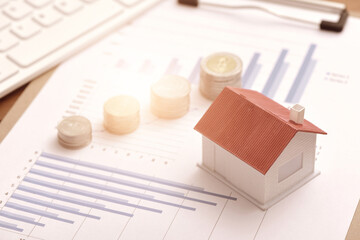 A small house, coins, and computer keyboard placed on a data blueprint