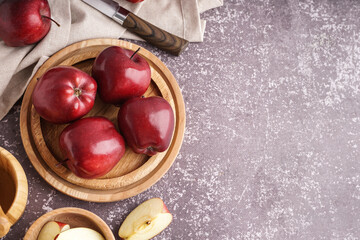 Wooden plate with fresh red apples on dark background