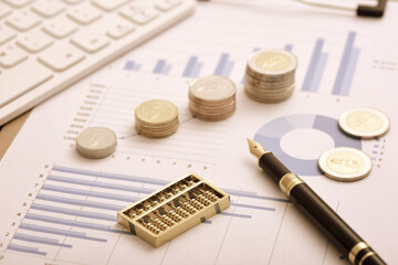 Coins, abacuses, and other office supplies placed on financial data reports