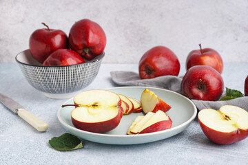 Wooden plate and bowl with fresh red apples on white background