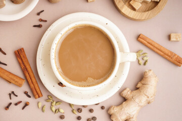 Cup of delicious masala tea with different spices on brown background