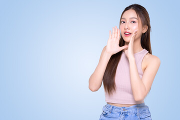 Beautiful young Asian woman with open mouths raising hands screaming announcement on isolated blue background. Facial and skin care concept for commercial advertising.