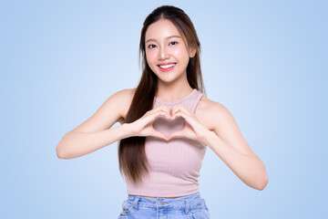 Attractive Asian woman feels happy and maks romantic hand sign heart shape isolated on blue background. People affection and care concept.