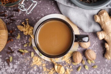 Cup of tasty masala tea with different spices on grunge background, closeup