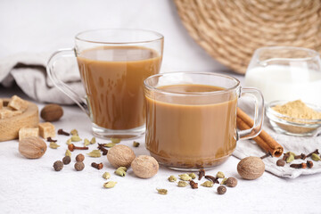 Glass cups of tasty masala tea with different spices on light background, closeup