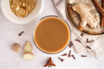 Glass of tasty masala tea with different spices on light background, closeup