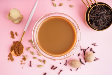 Obraz na płótnie Canvas Glass of tasty masala tea with different spices on pink background, closeup