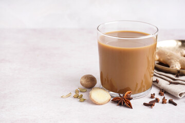 Glass of tasty masala tea with different spices on light background, closeup