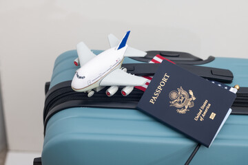 US passport lies on a suitcase next to a US flag and a toy airplane.Travel concept.