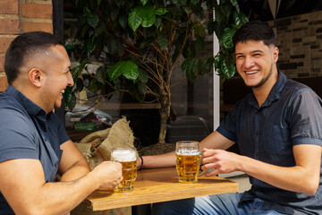 Two men are sitting at a table with two glasses of beer