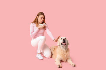 Young woman with napkin and dog suffering from allergy on pink background