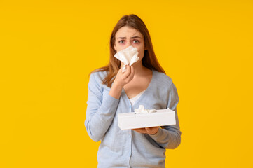 Young woman with tissue box suffering from allergy on yellow background - obrazy, fototapety, plakaty