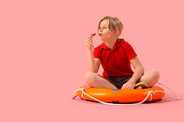 Happy little girl lifeguard with ring buoy whistling on pink background