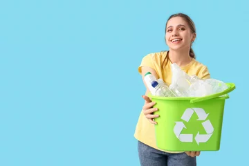 Gordijnen Young woman holding recycle bin with plastic garbage on blue background. Waste sorting concept © Pixel-Shot
