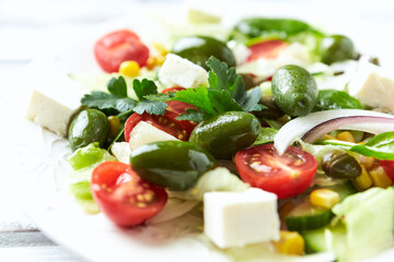 Healthy Salad with Feta Cheese, Green Olives, Baby Spinach, Cucumber, Cherry Tomatoes and Capers. Bright background. Close up.