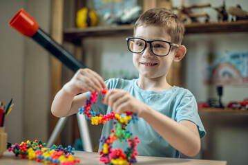A child boy in the children's room is playing with a toy constructor for teaching the science of chemistry. Assembling molecules from elements. Children's scientific education - 785857128