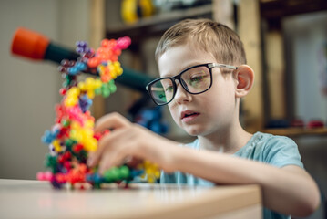A child boy in the children's room is playing with a toy constructor for teaching the science of...