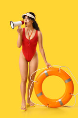 Beautiful young shocked African-American female lifeguard with ring buoy and megaphone on yellow...