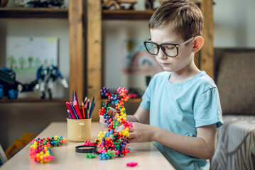 A child boy in the children's room is playing with a toy constructor for teaching the science of chemistry. Assembling molecules from elements. Children's scientific education - 785858189