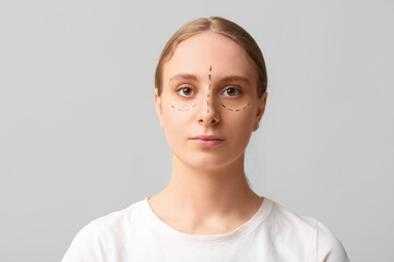 Young woman with marks on her face against grey background. Blepharoplasty concept