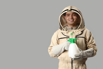 Male beekeeper with sprayer on light background
