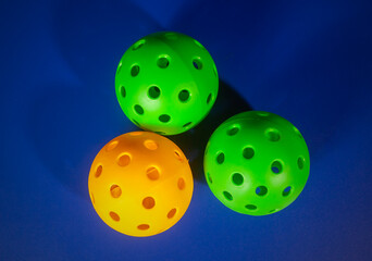 Colorful Pickleball ball in blue background. Pickleball is a new sport that is developing and starting to be popular with the public.