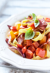 Pappardelle Pasta with Vegetables and fresh Basil and Ham on bright wooden Background. Close up.	
