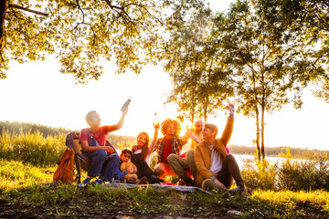 This image captures a heartwarming scene of a multi-generational family enjoying a picnic by a...