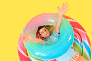 Cute little happy boy with inflatable mattress and ring on yellow background