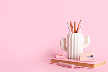 Pencil holder and book on pink background