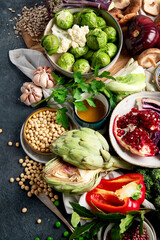 Vegan food. Pepper, broccoli, cabbage, garlic, mushrooms, pomegranate on a dark background